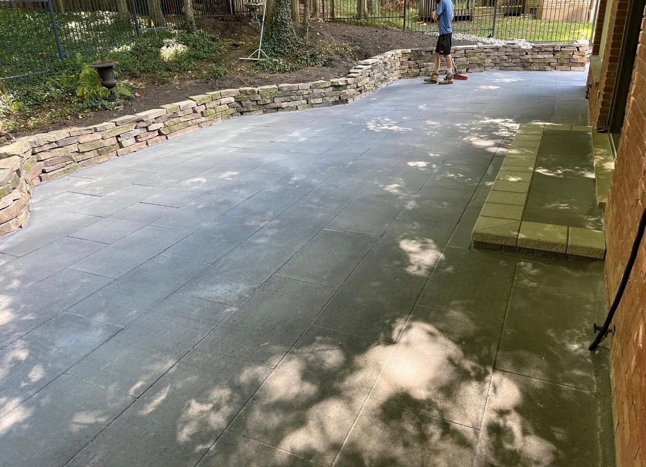 Slate patio with stone retaining wall and crew finishing by Leeonitis Contracting