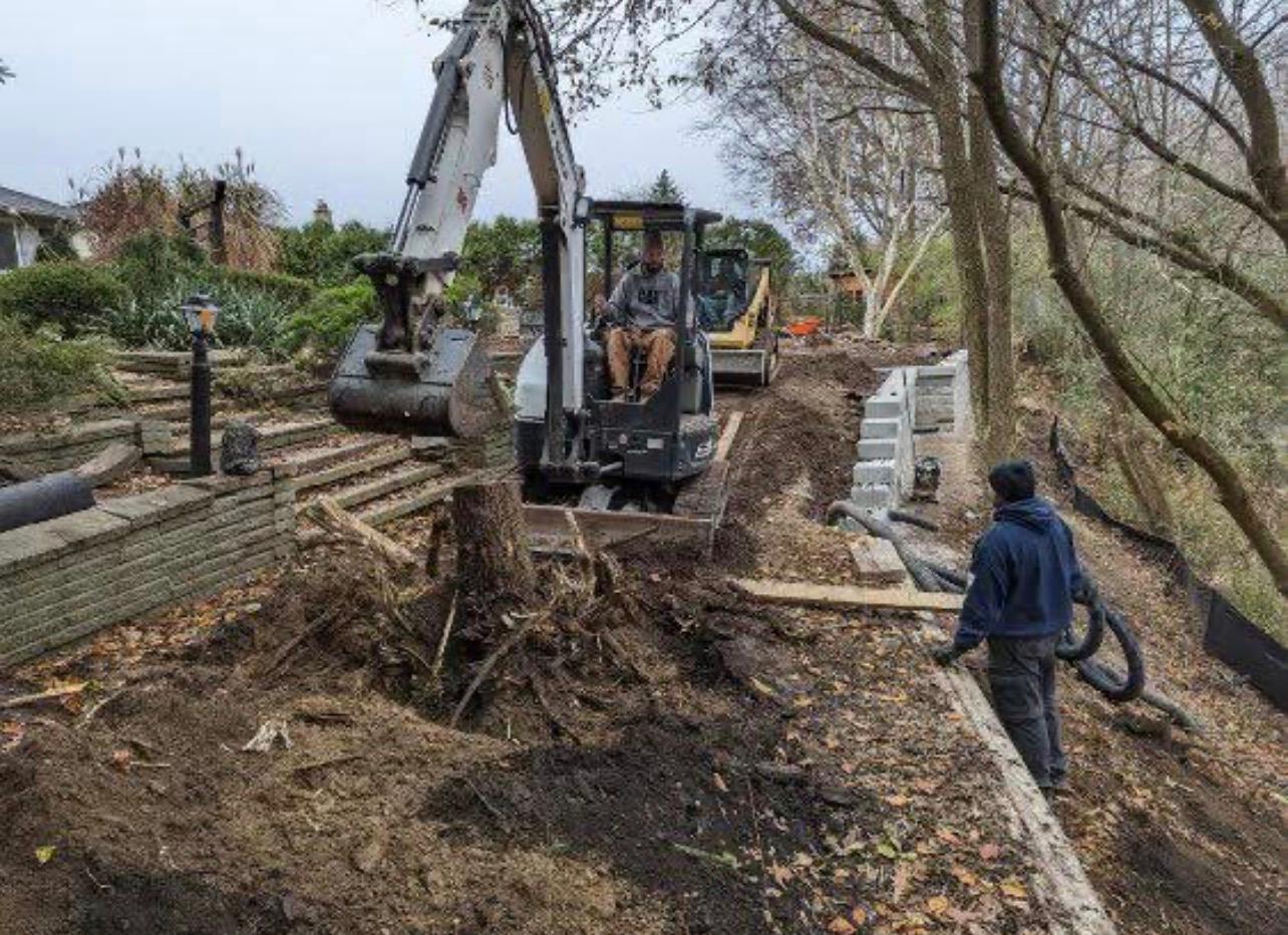 Excavator and crew working on retaining wall groundwork by Leeonitis Contracting