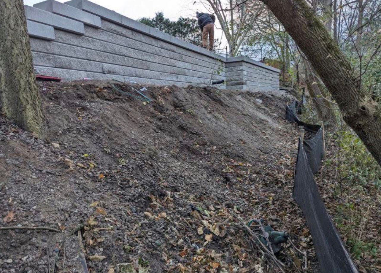 Large retaining wall being built on steep slope by Leeonitis Contracting